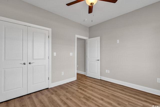 unfurnished bedroom featuring a closet, a ceiling fan, baseboards, and light wood finished floors