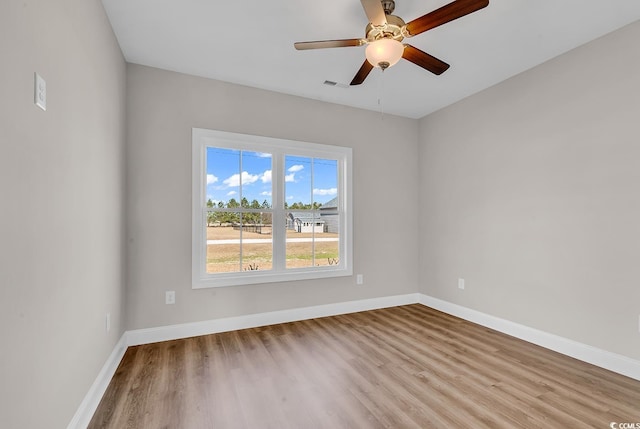 unfurnished room with visible vents, baseboards, wood finished floors, and a ceiling fan