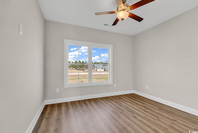 empty room featuring visible vents, wood finished floors, baseboards, and ceiling fan