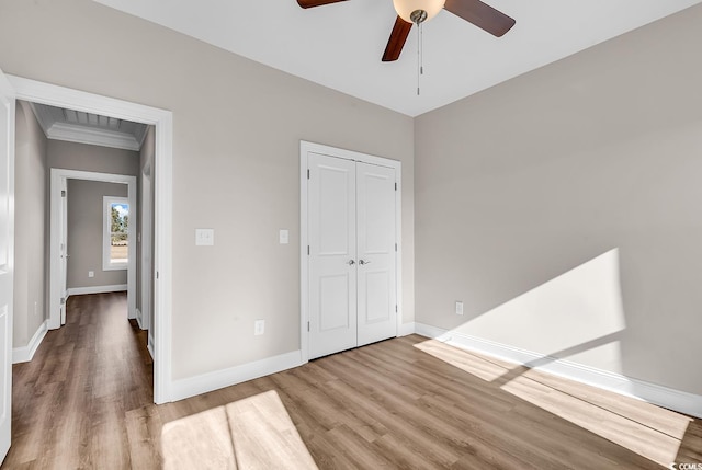 unfurnished bedroom featuring ceiling fan, a closet, baseboards, and wood finished floors