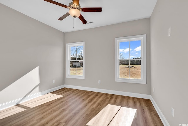 unfurnished room featuring visible vents, wood finished floors, baseboards, and ceiling fan