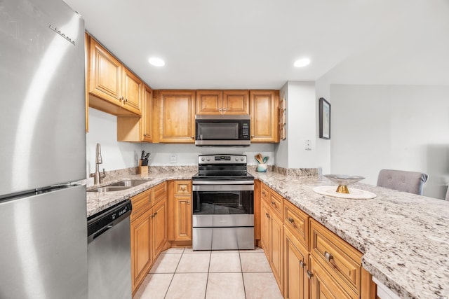 kitchen featuring a kitchen breakfast bar, light stone countertops, appliances with stainless steel finishes, sink, and light tile patterned flooring