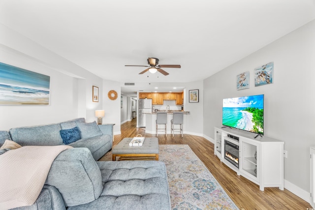 living room featuring light wood-type flooring and ceiling fan