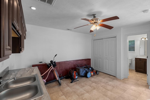 kitchen featuring a textured ceiling, sink, ceiling fan, and dark brown cabinetry