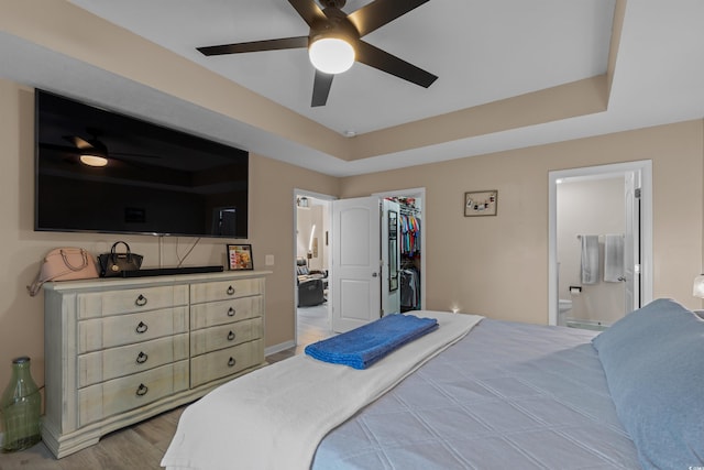 bedroom with light hardwood / wood-style flooring, connected bathroom, ceiling fan, a closet, and a spacious closet