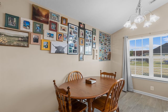 dining space with vaulted ceiling, a chandelier, and light hardwood / wood-style flooring