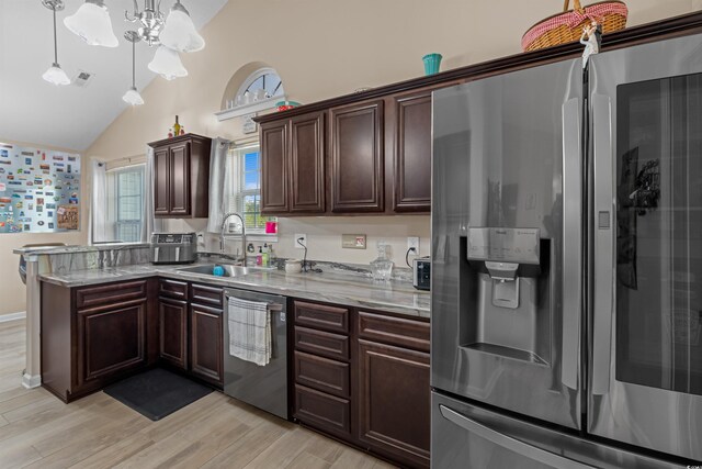 kitchen featuring light wood-type flooring, decorative light fixtures, stainless steel appliances, light stone counters, and sink