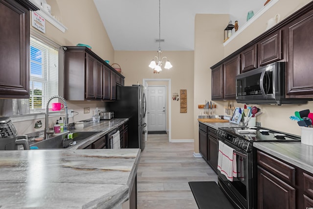 kitchen featuring an inviting chandelier, decorative light fixtures, appliances with stainless steel finishes, sink, and light wood-type flooring