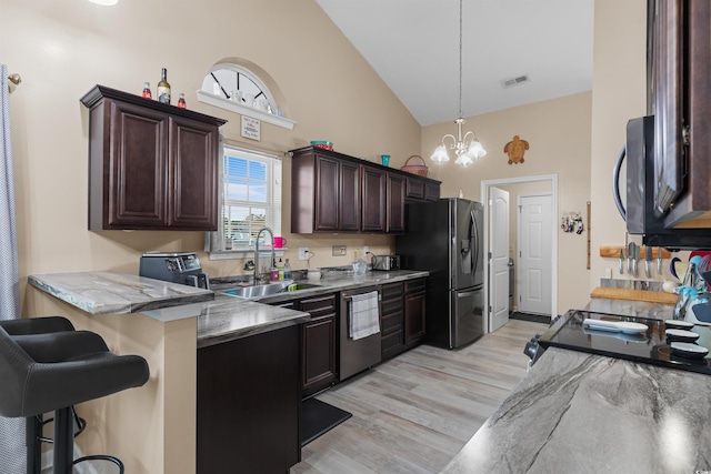 kitchen with high vaulted ceiling, a notable chandelier, a kitchen breakfast bar, sink, and appliances with stainless steel finishes