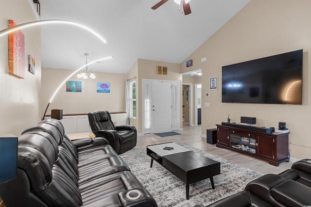 living room featuring lofted ceiling, ceiling fan with notable chandelier, and light hardwood / wood-style floors