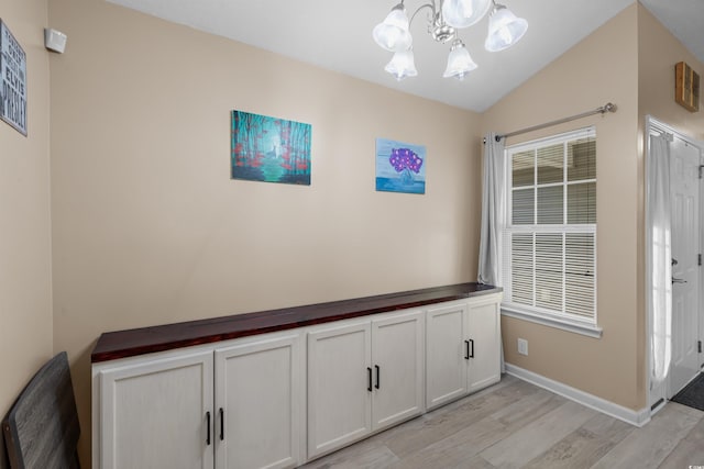 interior space featuring lofted ceiling, light hardwood / wood-style flooring, and an inviting chandelier