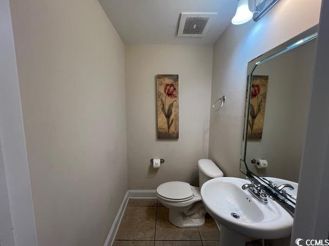 bathroom with toilet, sink, and tile patterned floors