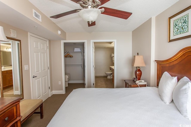 carpeted bedroom featuring ceiling fan, ensuite bathroom, and a textured ceiling