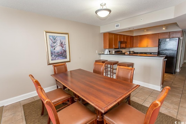 tiled dining area featuring a textured ceiling