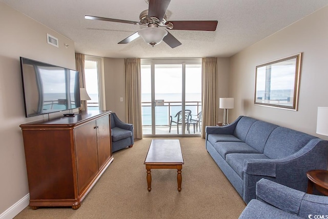 living room with a textured ceiling, ceiling fan, and light colored carpet