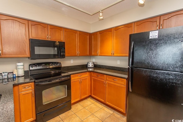 kitchen featuring a textured ceiling, black appliances, and light tile patterned floors