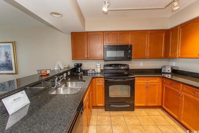 kitchen featuring light tile patterned flooring, a textured ceiling, black appliances, dark stone counters, and sink