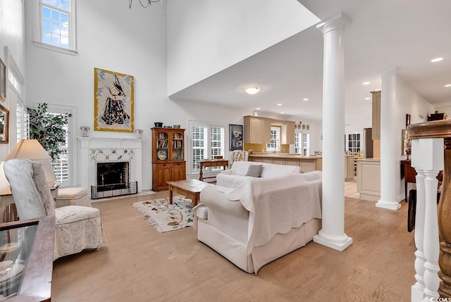 living room with a fireplace, a towering ceiling, and light hardwood / wood-style floors