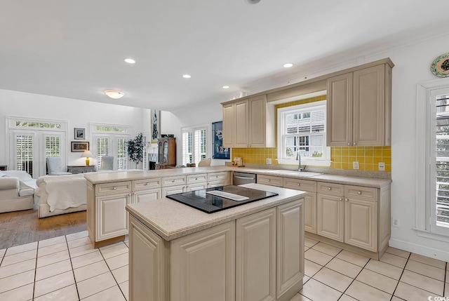 kitchen featuring a kitchen island, sink, cream cabinets, kitchen peninsula, and black electric stovetop