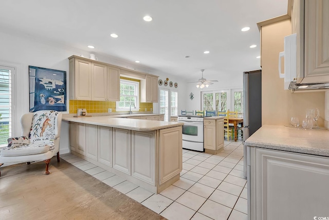 kitchen featuring light hardwood / wood-style flooring, kitchen peninsula, cream cabinets, and white stove