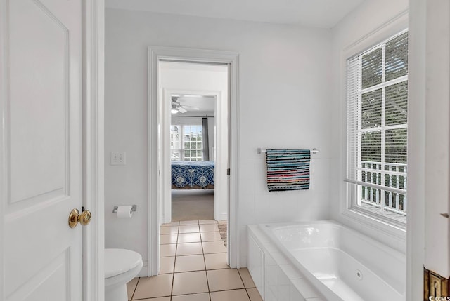 bathroom with tile patterned flooring, tiled bath, a wealth of natural light, and toilet