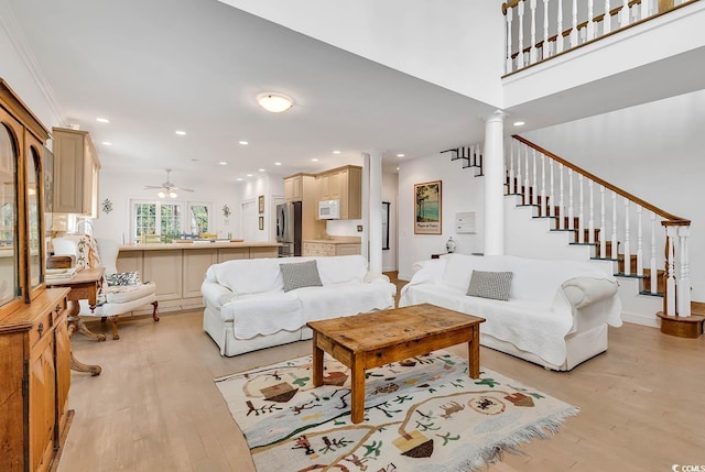 living room with decorative columns, ceiling fan, and light hardwood / wood-style flooring