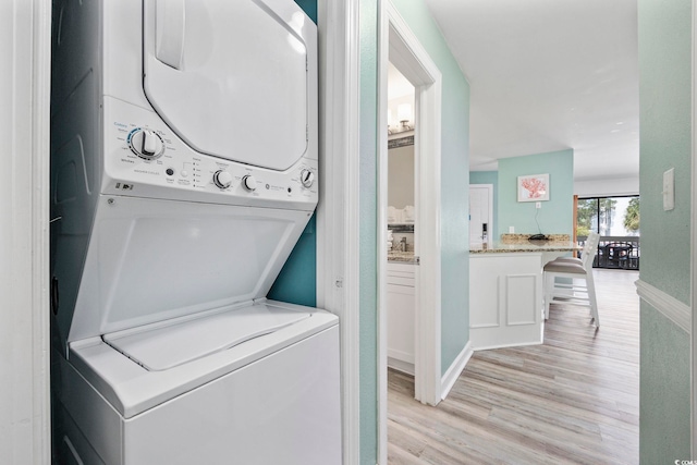 washroom featuring stacked washing maching and dryer and light hardwood / wood-style floors