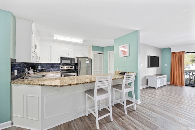 kitchen featuring white cabinets, light hardwood / wood-style flooring, appliances with stainless steel finishes, sink, and decorative backsplash