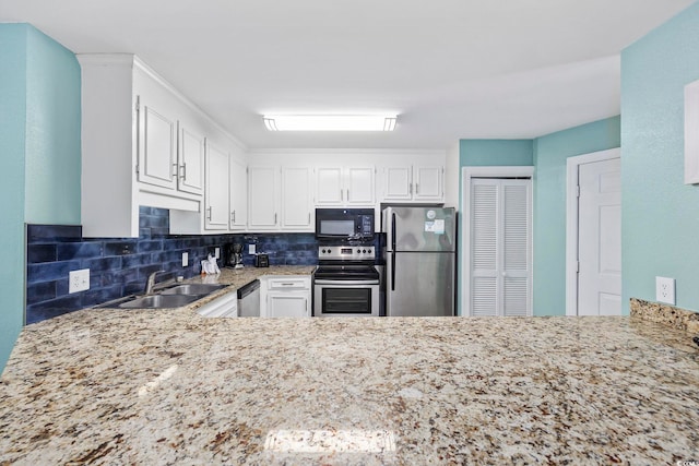 kitchen featuring white cabinets, light stone countertops, stainless steel appliances, and sink