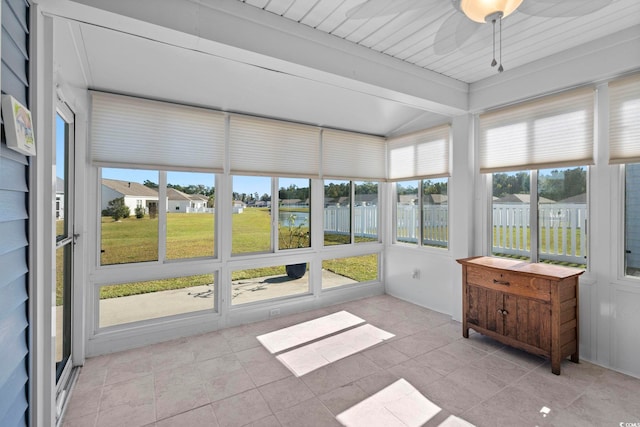 sunroom / solarium with a water view, ceiling fan, beamed ceiling, and a wealth of natural light