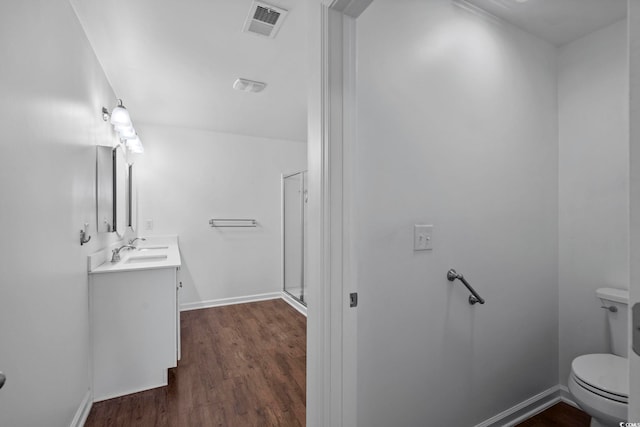 bathroom featuring vanity, wood-type flooring, toilet, and walk in shower