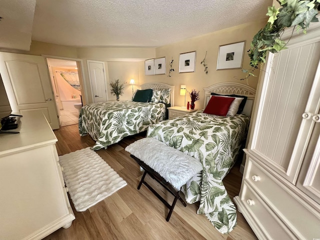 bedroom featuring connected bathroom, light hardwood / wood-style floors, and a textured ceiling