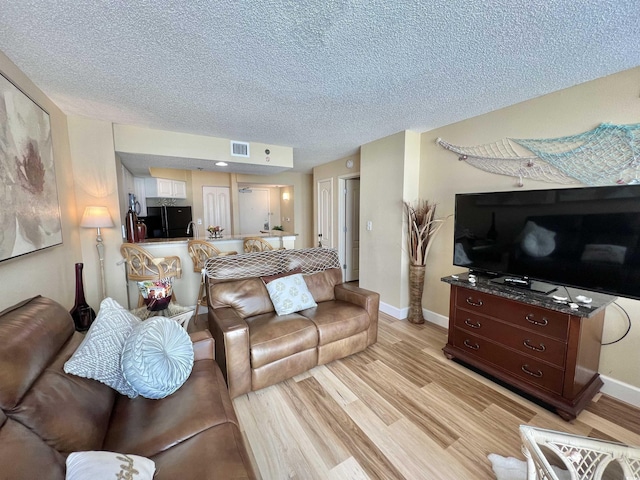 living room featuring light hardwood / wood-style flooring and a textured ceiling