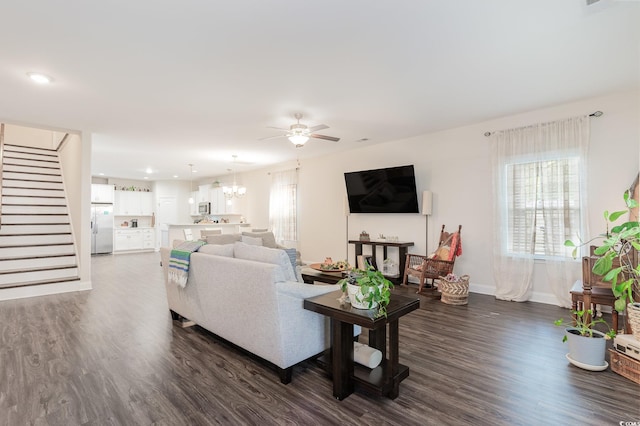 living room with dark hardwood / wood-style flooring and ceiling fan with notable chandelier