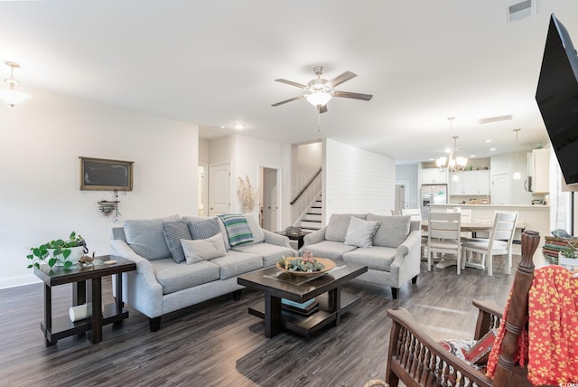 living room featuring ceiling fan with notable chandelier and dark hardwood / wood-style flooring