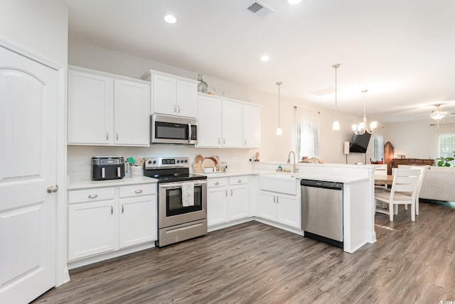 kitchen featuring appliances with stainless steel finishes, kitchen peninsula, decorative light fixtures, and white cabinetry