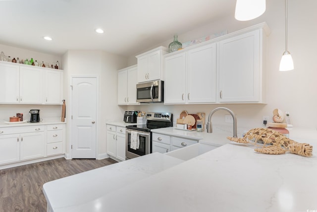 kitchen with white cabinetry, stainless steel appliances, wood-type flooring, and decorative light fixtures