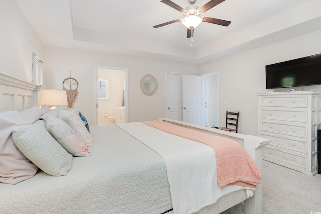 bedroom featuring carpet floors, ensuite bath, a raised ceiling, and ceiling fan