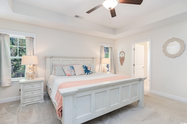 carpeted bedroom featuring a raised ceiling and ceiling fan