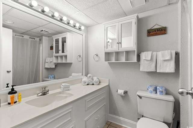 bathroom with vanity, a drop ceiling, tile patterned floors, and toilet