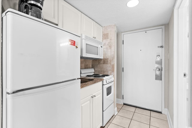 kitchen with a textured ceiling, light tile patterned floors, white cabinets, and white appliances