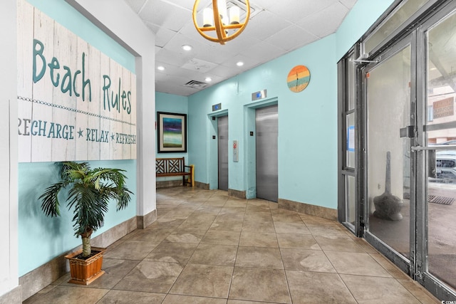 corridor with elevator, tile patterned floors, and a drop ceiling