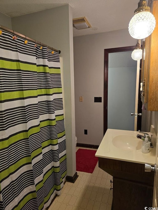 bathroom with a textured ceiling, vanity, and toilet