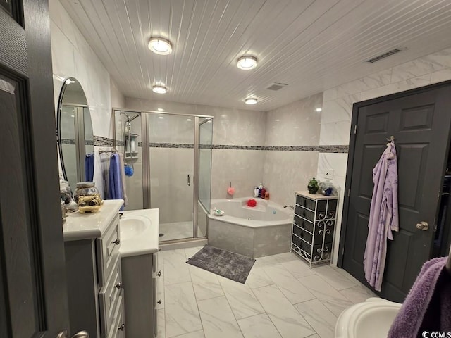 bathroom with vanity, shower with separate bathtub, and tile walls