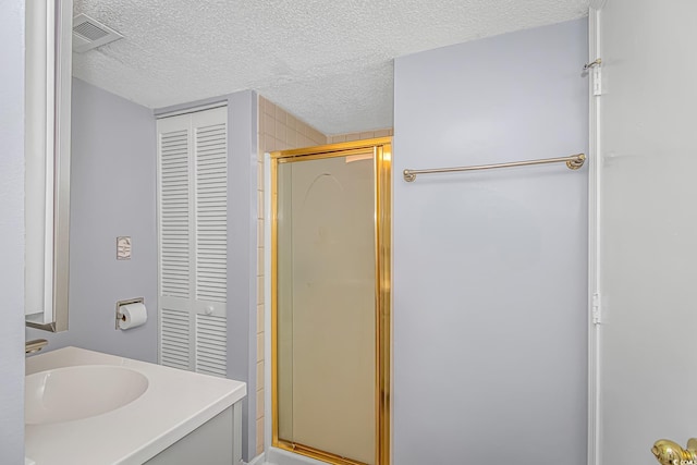 bathroom with walk in shower, vanity, and a textured ceiling