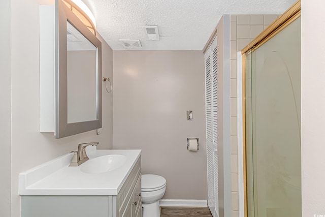 bathroom with toilet, an enclosed shower, a textured ceiling, vanity, and hardwood / wood-style floors