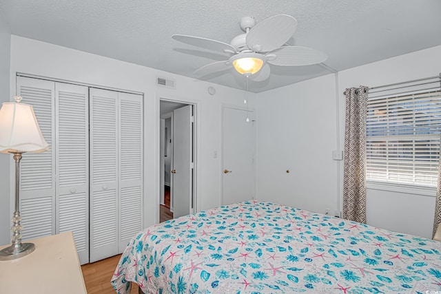 bedroom featuring ceiling fan, a textured ceiling, light wood-type flooring, and a closet