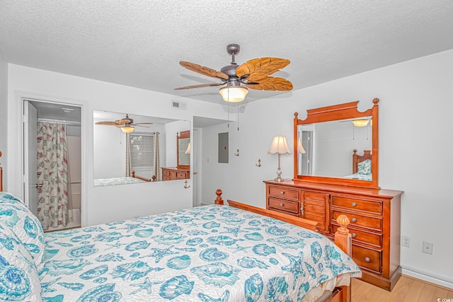 bedroom featuring ceiling fan, electric panel, a textured ceiling, and light wood-type flooring