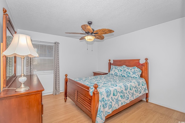 bedroom with ceiling fan, light hardwood / wood-style floors, and a textured ceiling