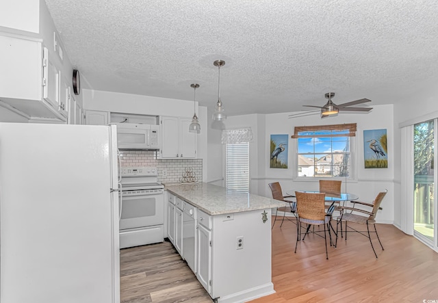 kitchen featuring white appliances, light stone counters, white cabinets, decorative light fixtures, and kitchen peninsula